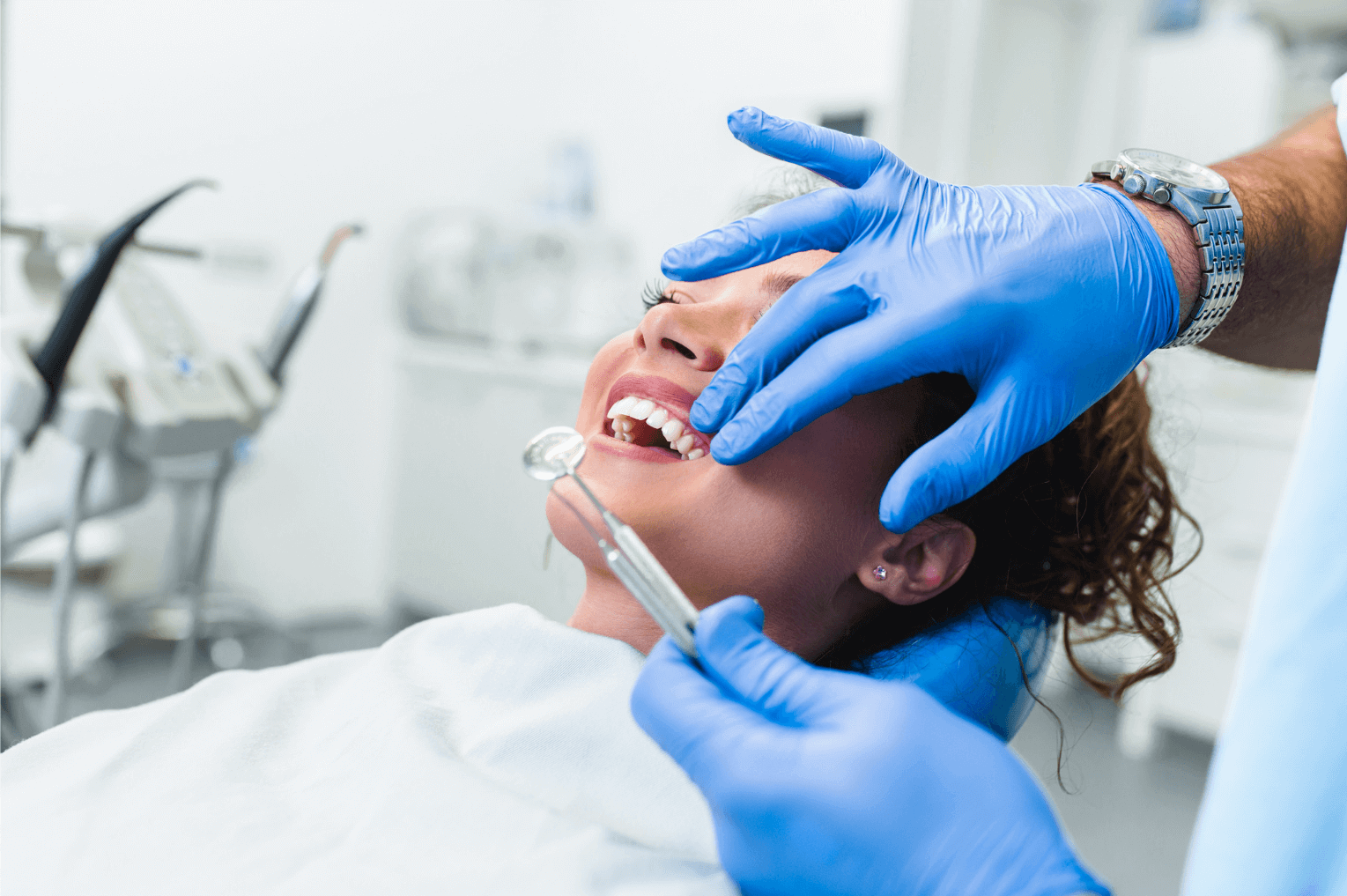 a Wimpole Street dentist wearing blue medical gloves while checking a patients mouth