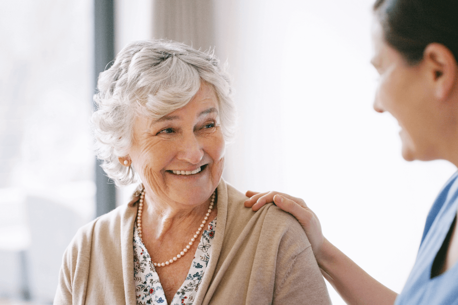 dentist placing his hand on a smiling elderly woman's shoulders