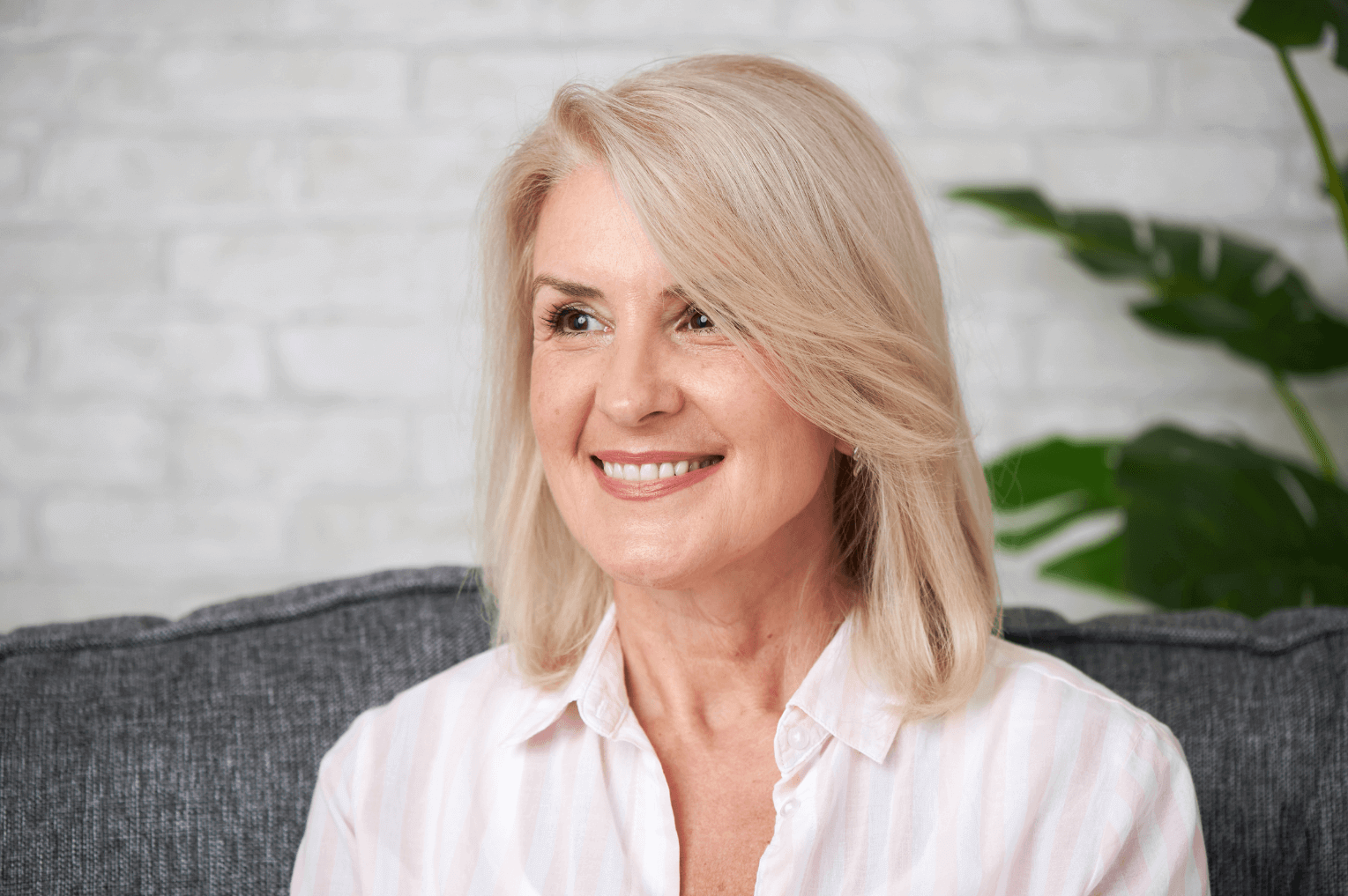 woman with blonde hair smiling, showing off her dental implants