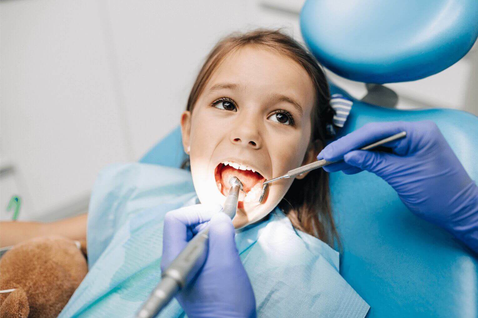 A young girl sat at the dentist with her mouth open