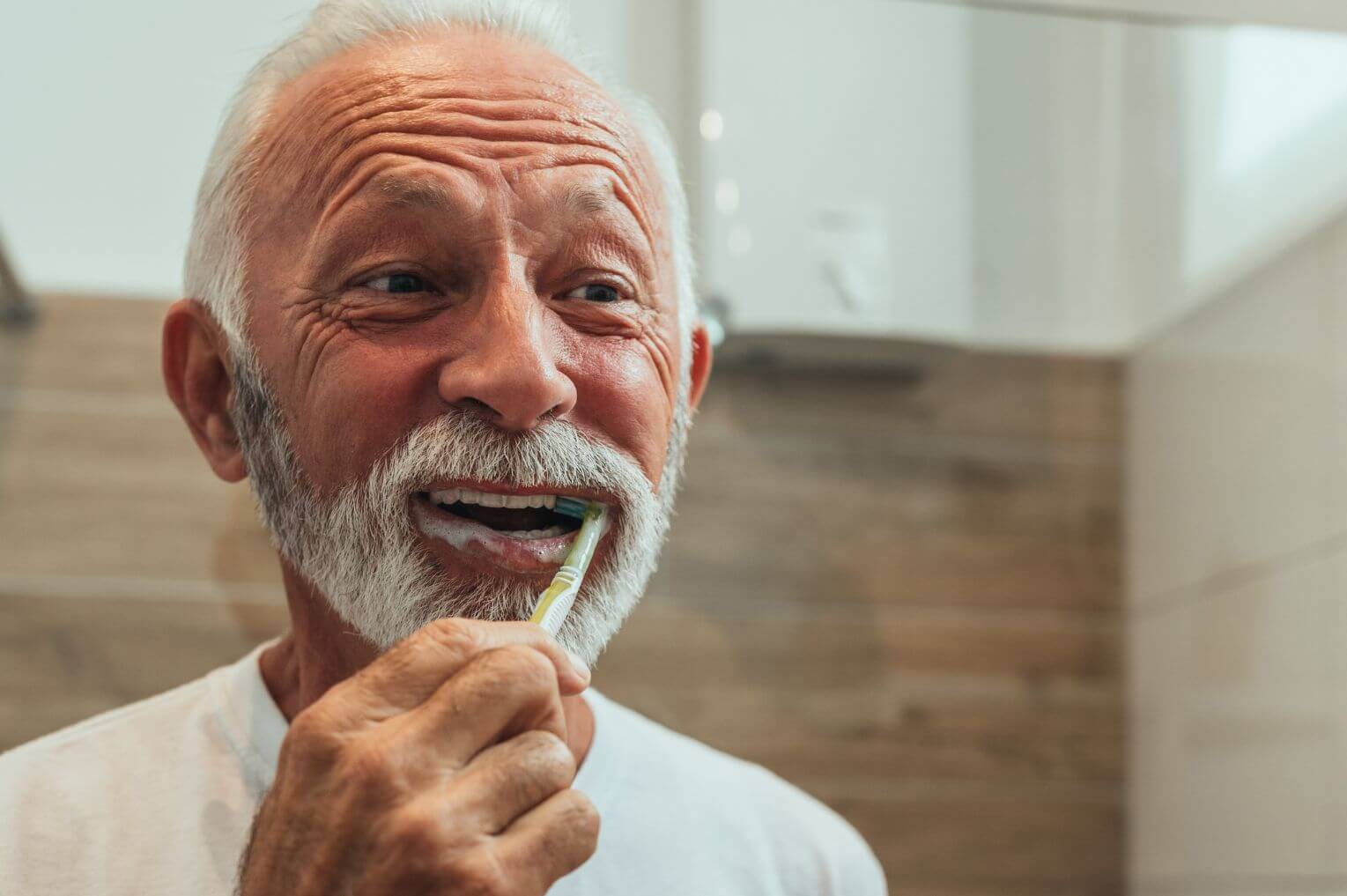 man brushing his teeth with dental implants, london