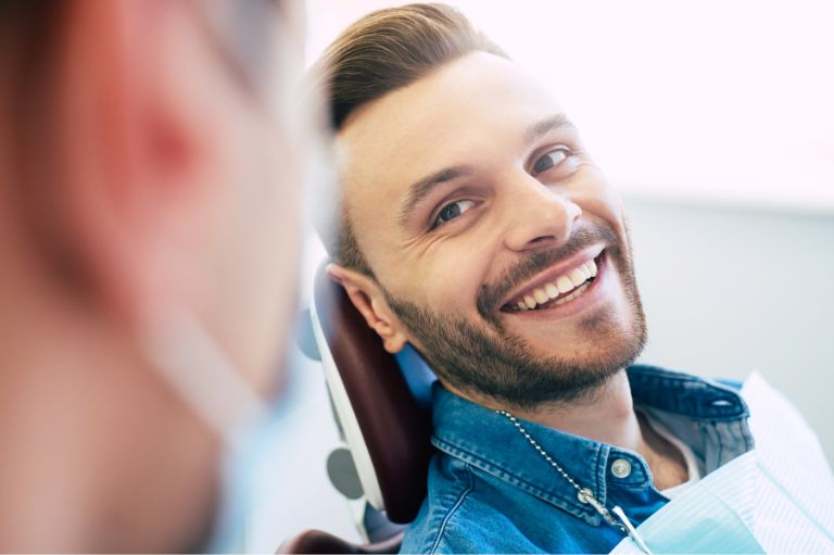 Man sat in dental chair, smiling with dental implants
